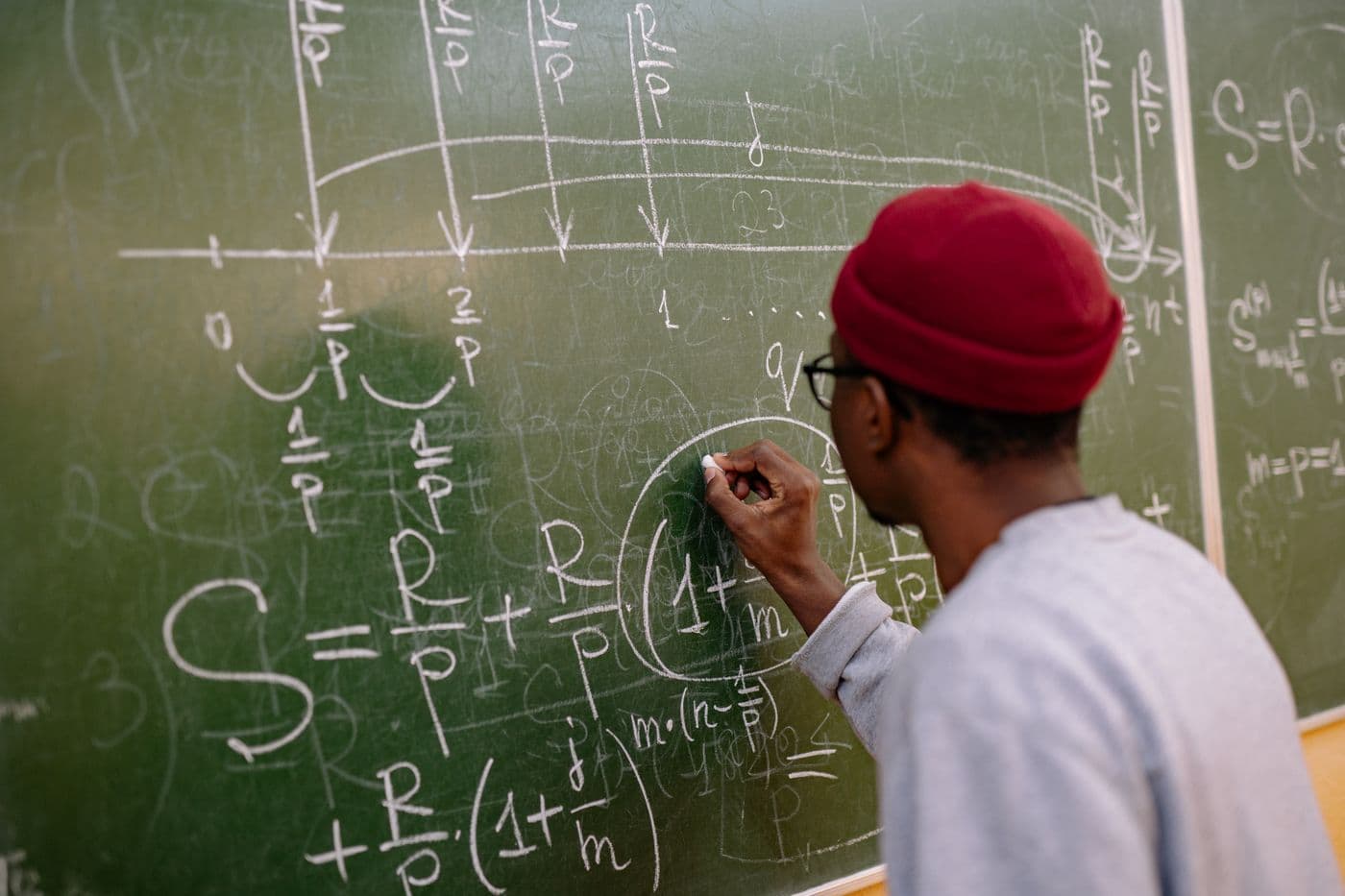 A professor writing equations on the chalkboard, mid-lecture